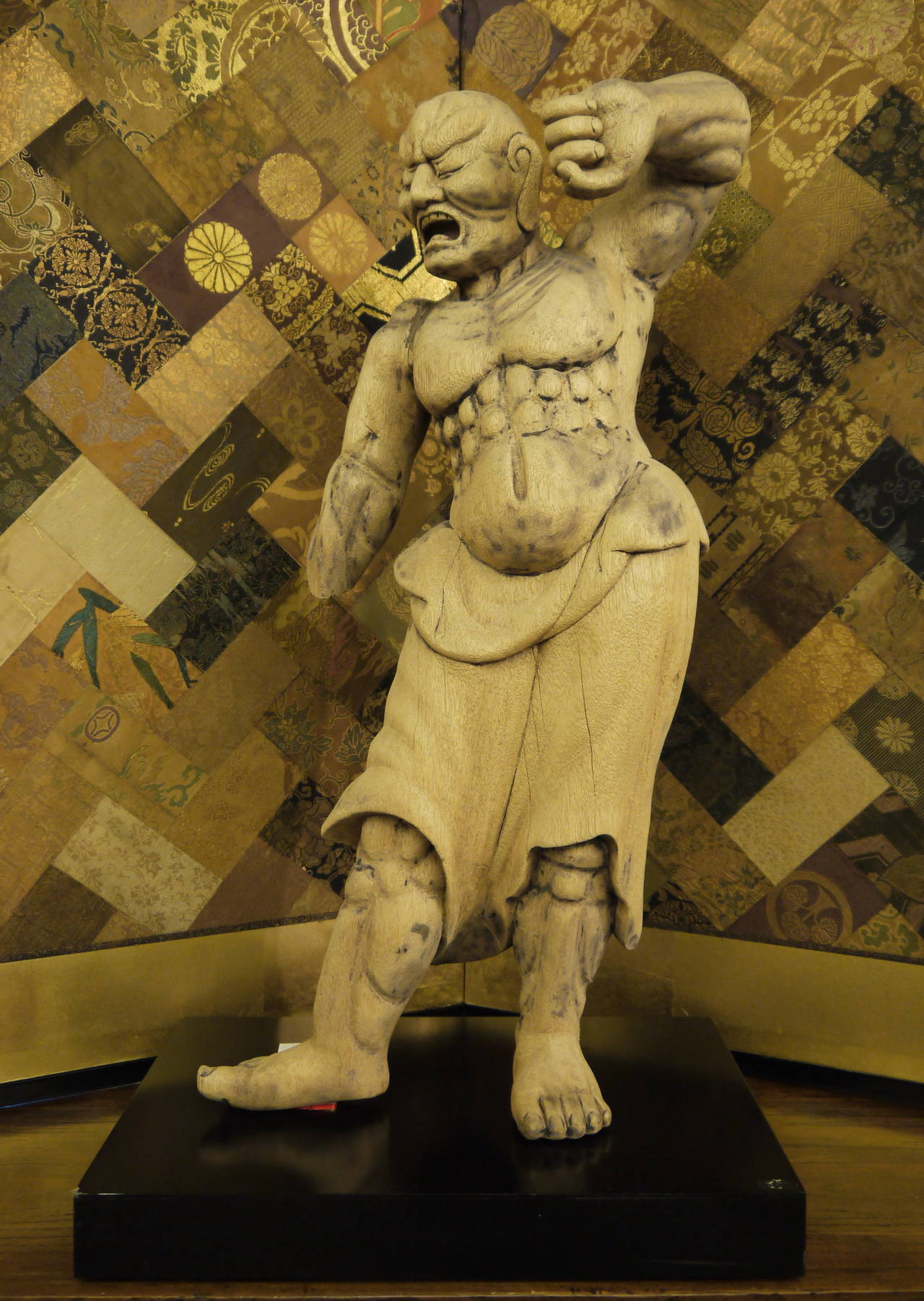 A large and dramatic muscled Nio guardian figure. 

Nio figures were placed outside Buddhist temples as protectors against evil spirits and to keep the temple free of demons and thieves.

This figure stands on a custom stand. It is 32 inches high