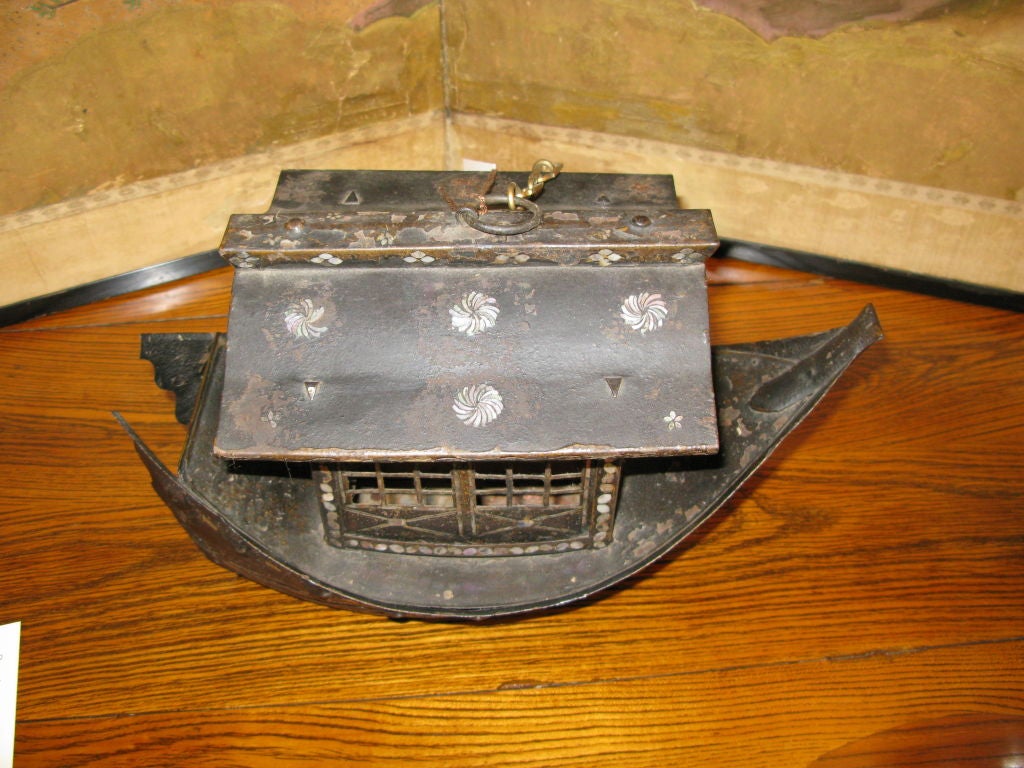 Japanese metal lantern in the form of a boat.<br />
<br />
With inlaid mother of pearl.  On the base of the boat, the mother of pearl creates a wave pattern.  It is elsewhere used to create borders, and on the roof it is in stylized floral