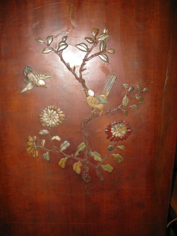 Age: Late 18th Century<br />
<br />
Chinese<br />
<br />
Double door cabinet in brown/red lacquer, with inlay of jade, ivory, mother of pearl, coral and carnelian.  <br />
<br />
Design of figures, pavillions and trees on front.<br />
<br