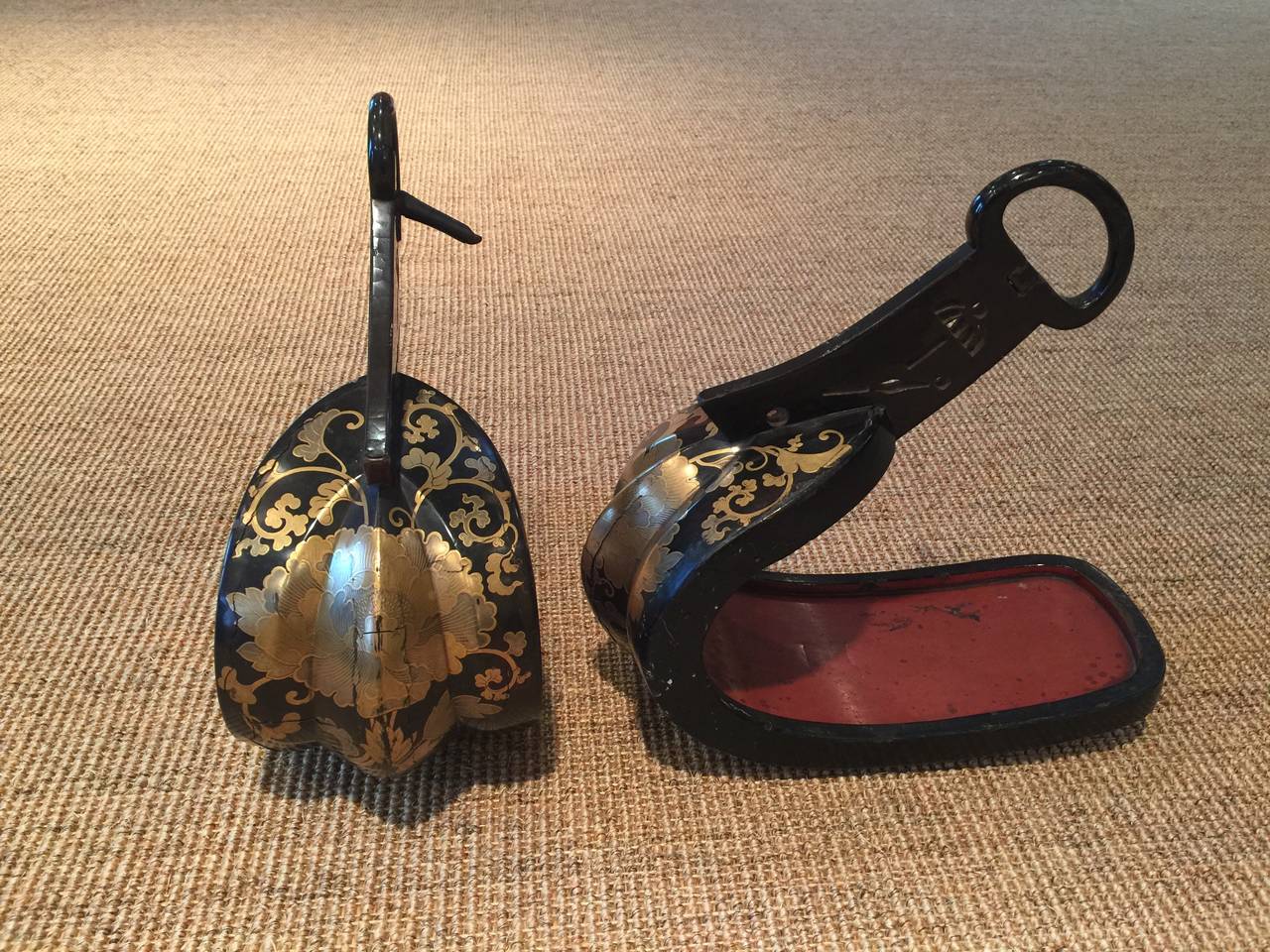 A lacquered pair of Japanese abumi - Samurai horse riding stirrups.

Metal, with black lacquer and gold leaf in a pattern of vines and flowers, with red lacquer interior.