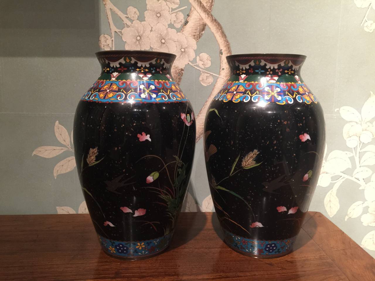 A very pretty and decorative pair of Japanese cloisonne vases with intricate borders and design of flying birds.