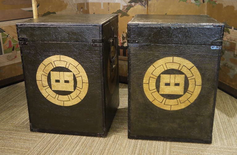 A pair of Hitsu of Yoroi (Samurai armor storage boxes), with black leather exterior, hinged lids and gold family crests on three sides.