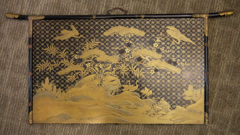 Wonderfully detailed antique wall panel. The background is dark lacquer and there is very finely detailed gilt lacquer design with cranes, pine trees and geometric patterns.