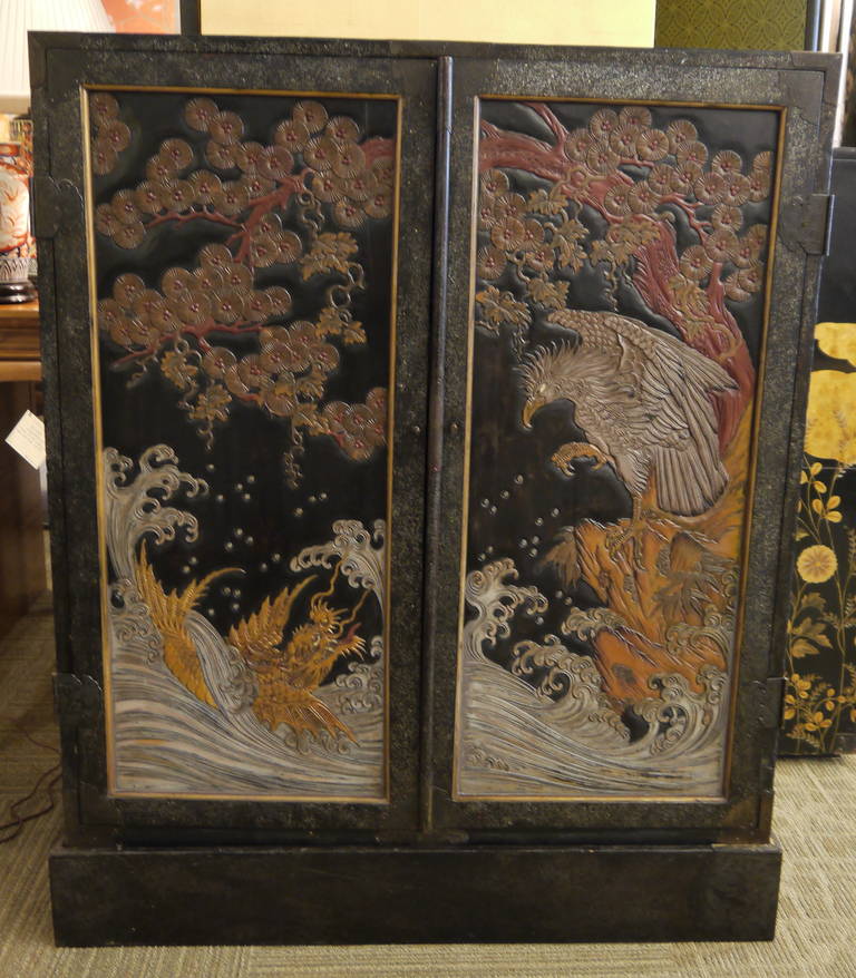 A stunning antique Japanese double door cabinet, with dramatic design of hawk and dragon on front. 

Black lacquer is inset with tiny pieces of mother-of-pearl.

Interior has drawers with gold crests. 

Inside of doors with gold makie lacquer
