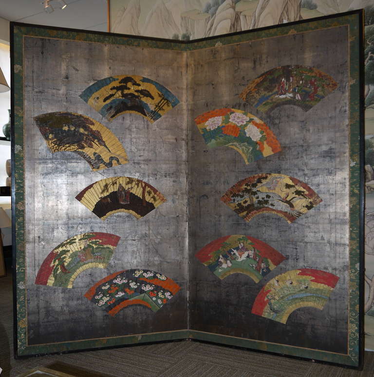 A fabulous large two panel screen with scattered fans of various ages (17th-19th century), applied to a silver leaf background.