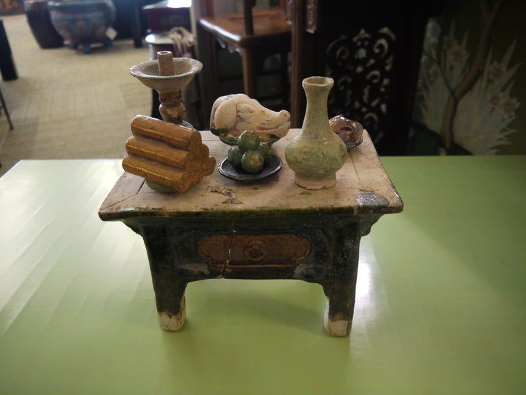 Chinese Ming Dynasty miniature altar table with six offerings, including vase, candle holder, food, pigs head, and pomegranates.

All items are pottery, partially glazed.