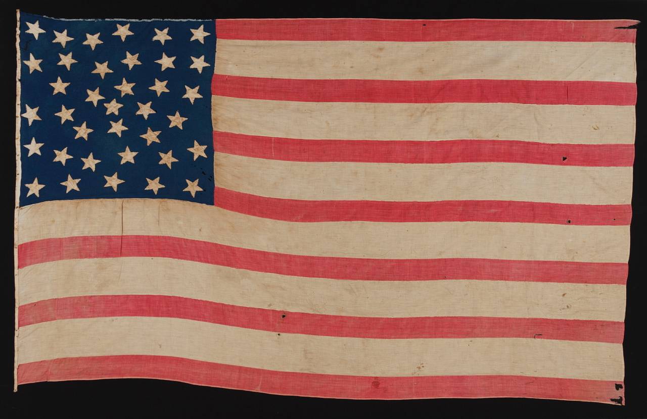36 STARS, A HOMEMADE FLAG OF THE CIVIL WAR ERA WITH AN EXCEPTIONAL RANDOM STAR PATTERN AND GREAT DISPARITY BETWEEN THE WIDTH OF THE RED AND WHITE STRIPES, NEVADA STATEHOOD, 1864-67: 

In the world of antique American flags there are nearly countless