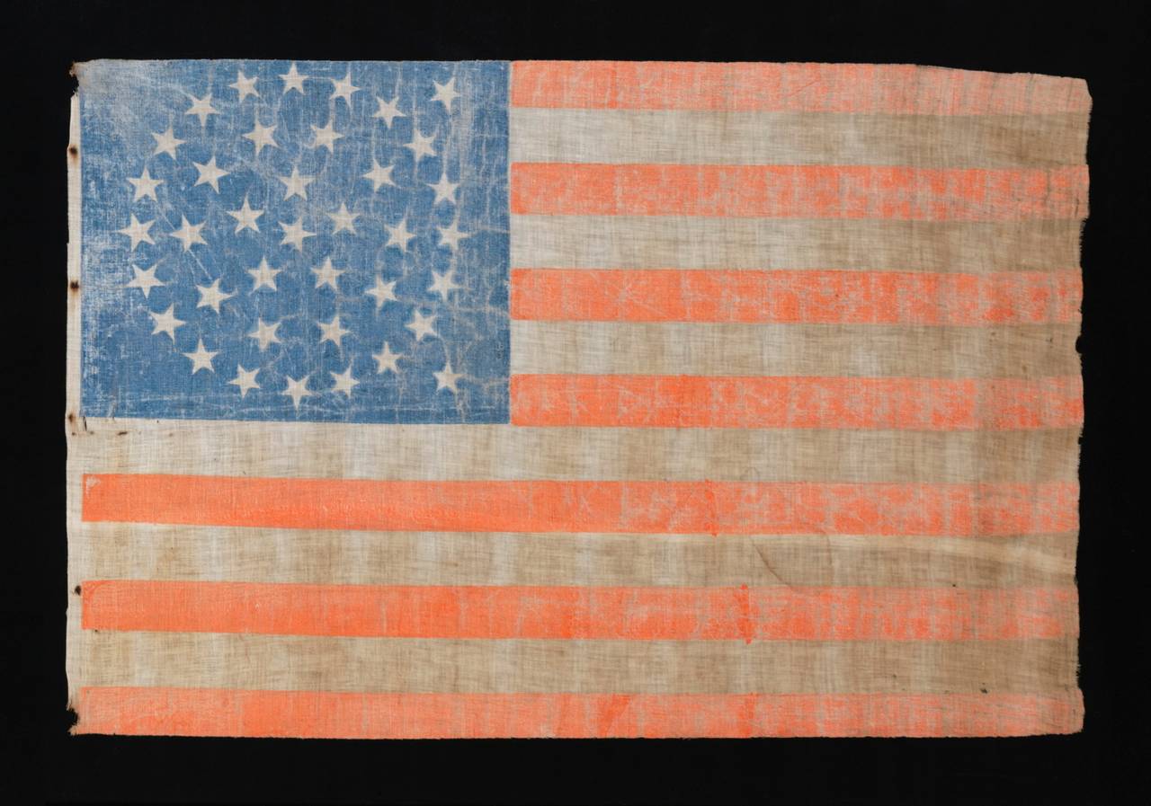 38 STARS IN A MEDALLION CONFIGURATION WITH 2 OUTLIERS, COLORADO STATEHOOD, 1876-1889, A LARGE EXAMPLE WITH ENDEARING WEAR FROM EXTENDED USE:

38 star American parade flag, block-printed by hand on coarse, glazed cotton, with endearing wear from