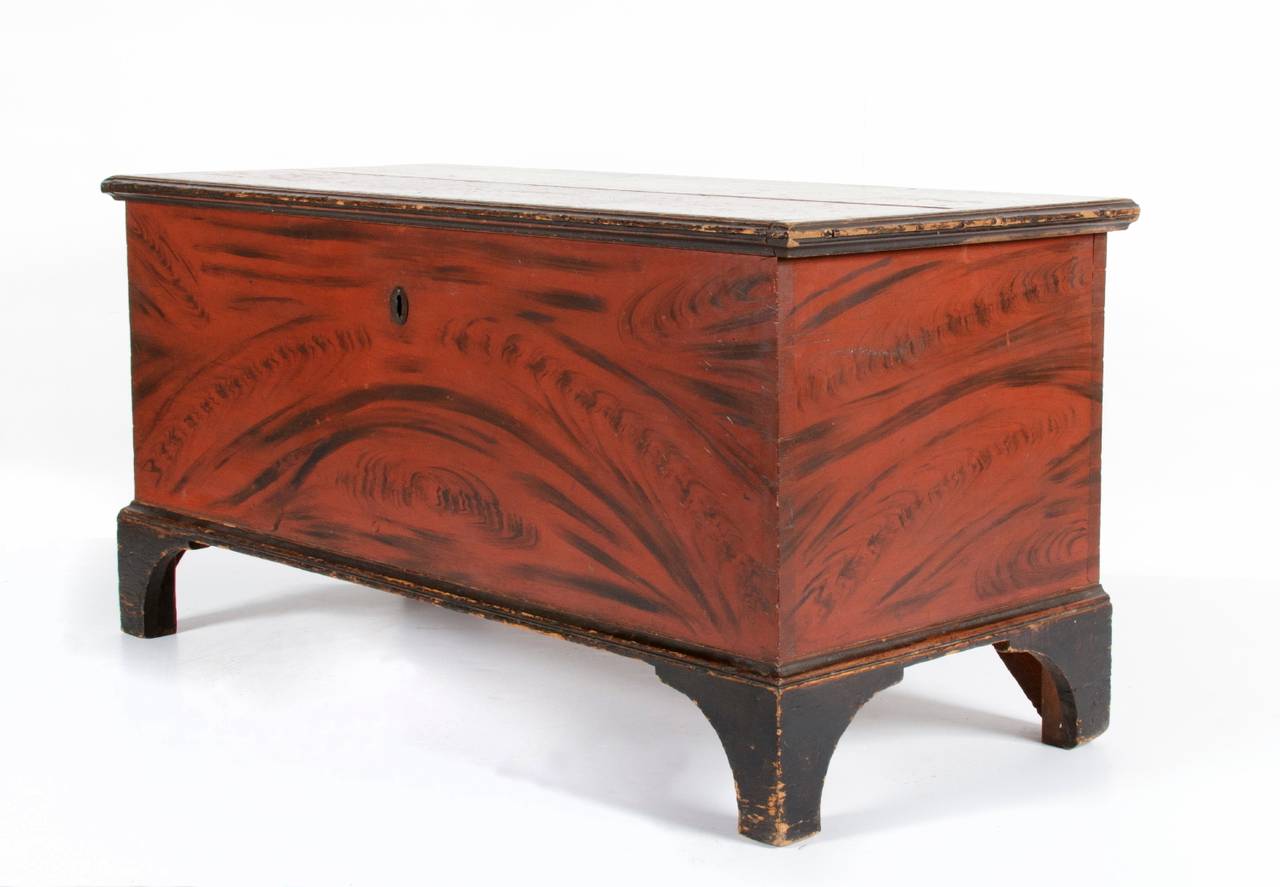 YORK COUNTY, PENNSYLVANIA BLANKET CHEST WITH RED AND BLACK STYLIZED DECORATION ON BLACK FEET, ca 1835:

York County, Pennsylvania blanket, made ca chest with an applied bracket base that has high scalloped feet. The case is painted a strong red that