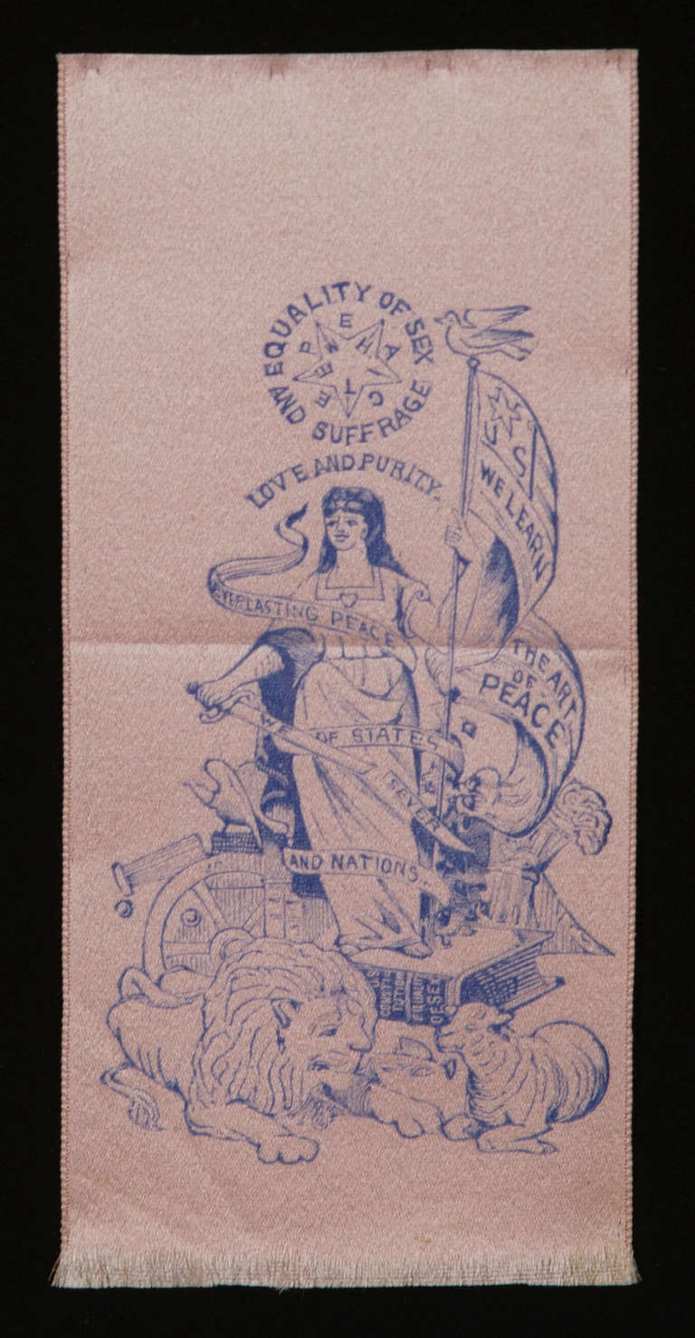 EARLY SUFFRAGETTE RIBBON WITH AN ALLEGORICAL FIGURE STANDING UPON THE U.S. CONSTITUTION BEFORE A LION AND LAMB, WITH A HOST OF GREAT SLOGANS OF THE WOMEN'S MOVEMENT:

Printed in blue on light pink silk satin, this great Suffrage Movement ribbon