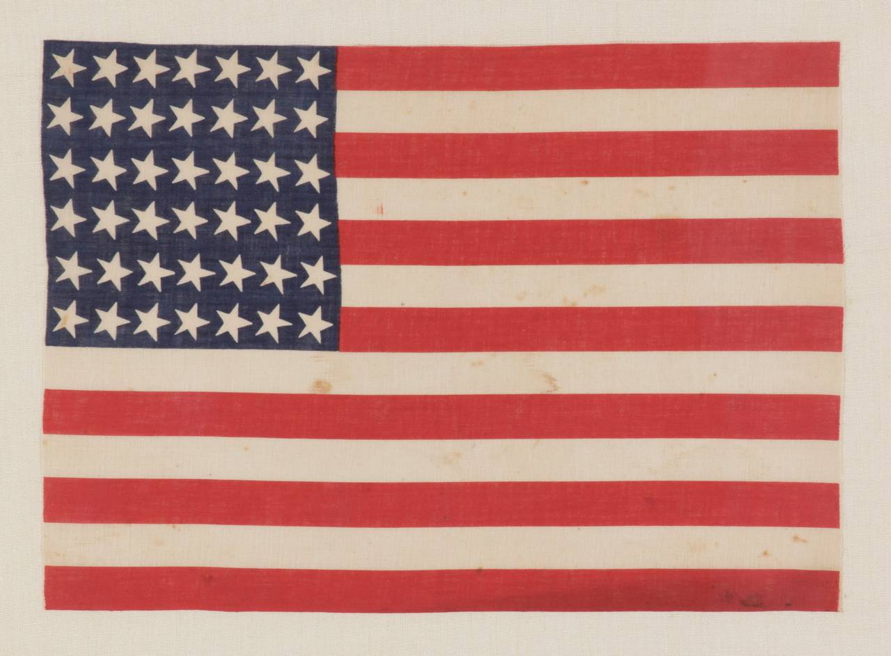 42 CANTED STARS, NEVER AN OFFICIAL STAR COUNT, 1889-1890, WASHINGTON STATEHOOD:

42 star American parade flag, printed on cotton. Note how the stars, which are arranged in a rectilinear fashion, are tilted at a uniform angle in the 1:00 position.