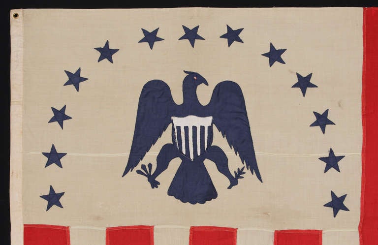 RARE REVENUE CUTTER SERVICE FLAG WITH A BLUE EAGLE AMID AN ARCH OF 13 BLUE STARS, ON A WHITE FIELD, AND AN UNUSUAL COUNT OF 17 VERTICAL RED AND WHITE STRIPES, CA 1880-1895:

United States Revenue Cutter Service flag, made in the period between 1880