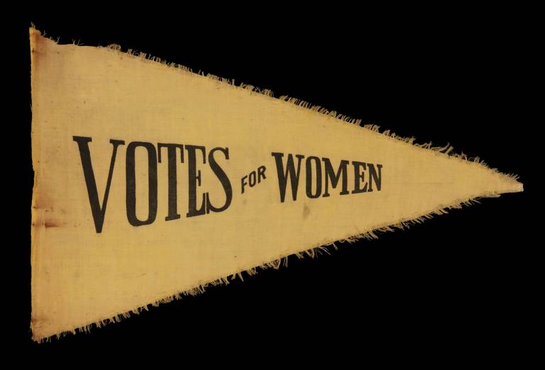 TRIANGULAR SUFFRAGETTE PENNANT WITH A CRUDE, PULLED WORK FRINGE AND TEXT THAT READS:  