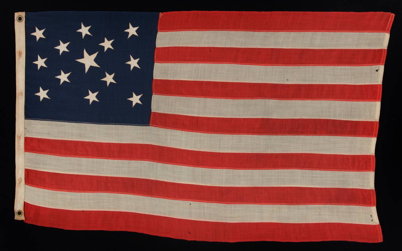 13 stars arranged in a highly unusual version of a 3-2-3-2-3 lineal star configuration that features a large center star; a small-scale flag of the 1890-1910 era:

 This 13 star antique American flag is of the type made during the last decade of