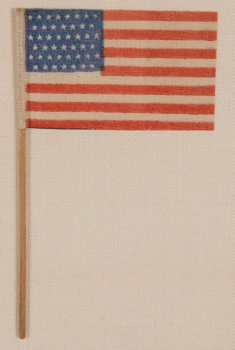 45 STARS, 1896-1907, UTAH STATEHOOD, SPANISH-AMERICAN WAR-ERA:

 45 star American national parade flag, printed on coarse, glazed cotton, affixed to its original wooden staff. The stars are arranged in staggered rows of 8-7-8-7-8, which was a