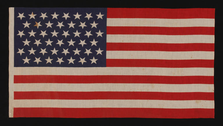 45 RATHER POINTY STARS IN LINEAR ROWS WITH “DANCING” OR “TUMBLING” ORIENTATION, ON AN ELONGATED PARADE FLAG OF THE 1896-1907 PERIOD, UTAH STATEHOOD: 

45 star American national parade flag, printed on cotton bunting. The stars are arranged in