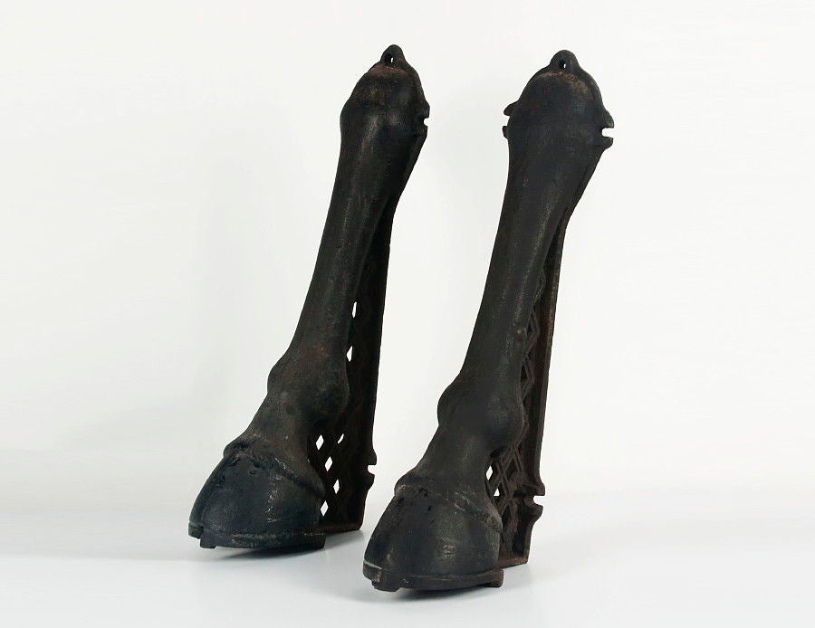 RARE CAST IRON BUILDING FENDERS/ CARRIAGE GUIDES IN THE FORM OF HORSE HOOVES, ATTRIBUTED TO WILLIAM ADAMS, PHILADELPHIA, CA 1870-90:

Pair of cast iron fenders, used to steer carriages away from the corners of buildings. A highly unusual form, in
