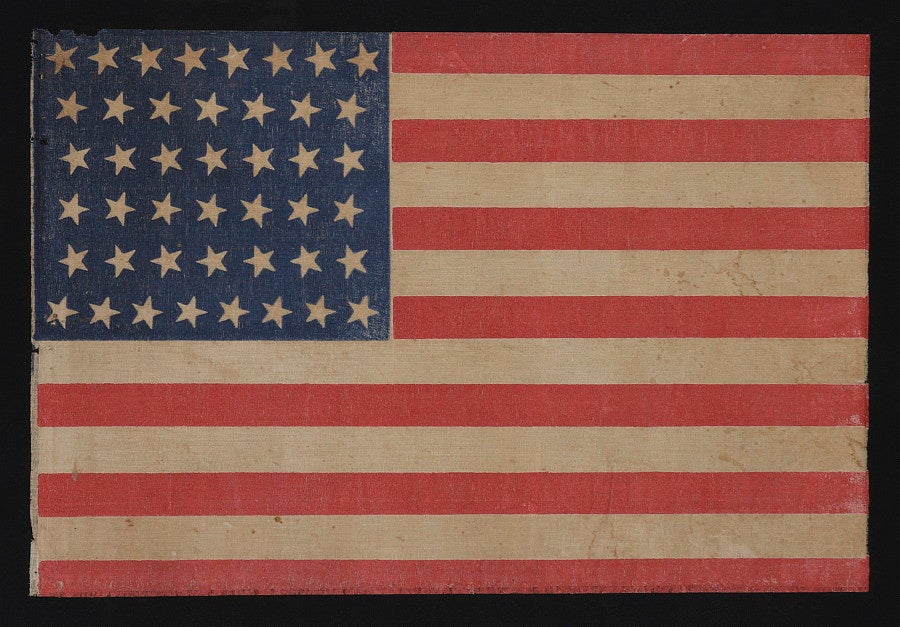 44 TILTING STARS IN AN HOURGLASS FORMATION, WYOMING STATEHOOD, 1890-1896:<br />
<br />
44 star American parade flag printed on coarse, glazed cotton. Note how the vertical alignment of the stars varies from row-to-row, each uniformly tilting in