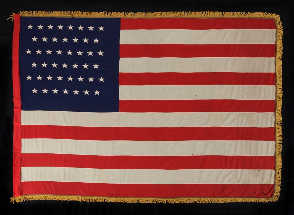 45 STARS, A VERY UNUSUAL MILITARY BATTLE FLAG, MADE OF MERINO WOOL WITH EMBROIDERED STARS, BOUND WITH BULLION TAPE AND TRIMMED WITH GOLD SILK FRINGE, UTAH STATEHOOD, 1896-1907, SPANISH-AMERICAN WAR ERA:

45 star American military battle flag, made