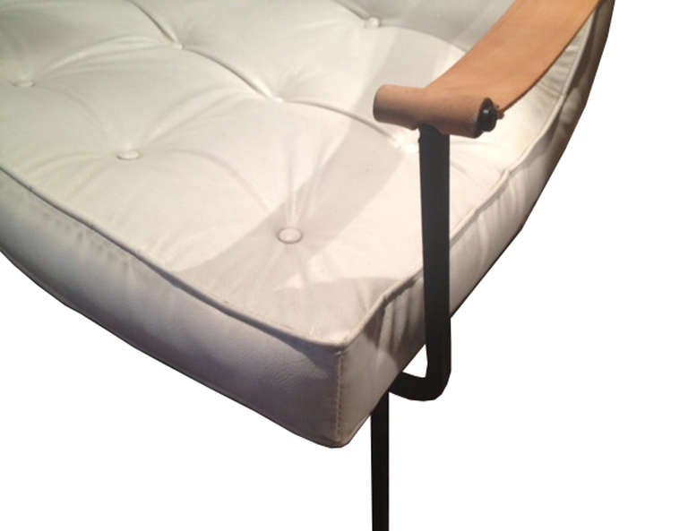 A modern sculptural lounge chair with wide curved seat and saddle arms attached to a curved iron frame.