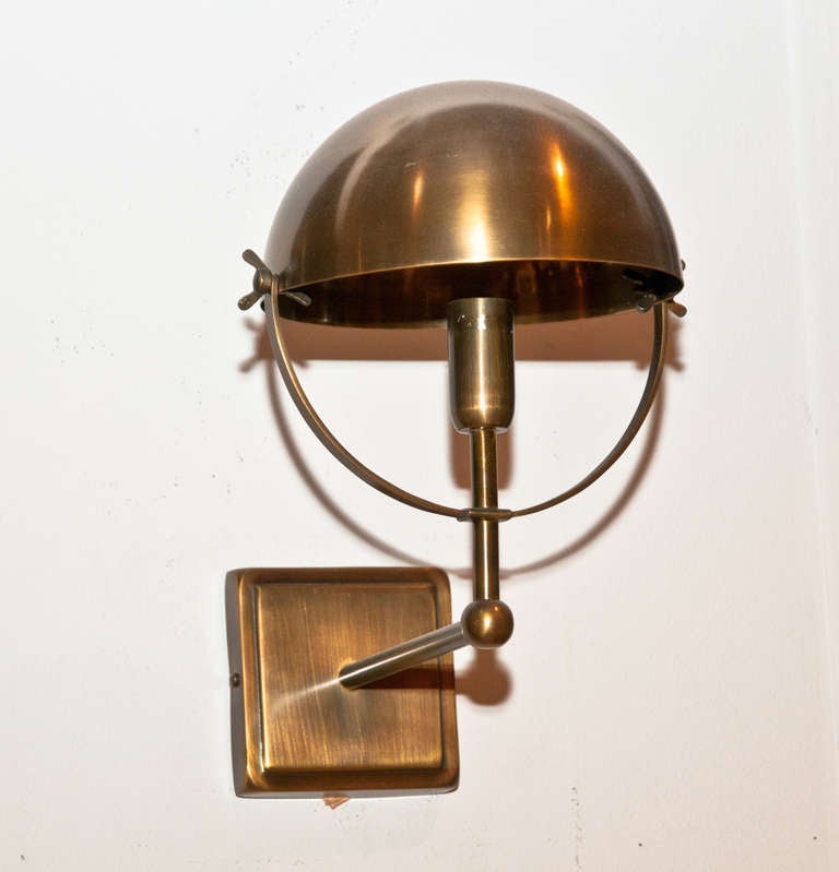 This large brass wall sconce is articulated. Its round shape recalls the 1950's but its gold color gives it an updated look.