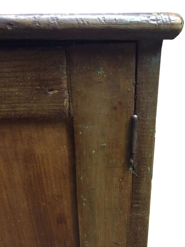 A solid wood antique armoire with chipped paint detail on the edges. 