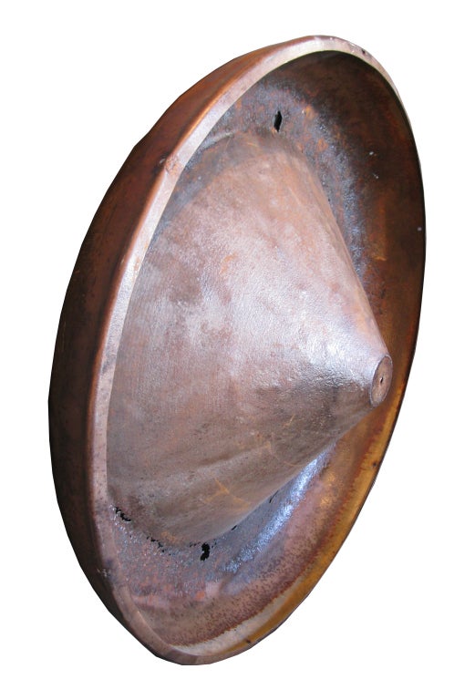 This copper tone, industrial metal disc makes a unique and interesting wall hanging.