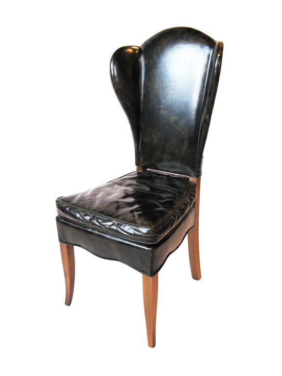 Elegant pair of leather upholstered wingback chairs.