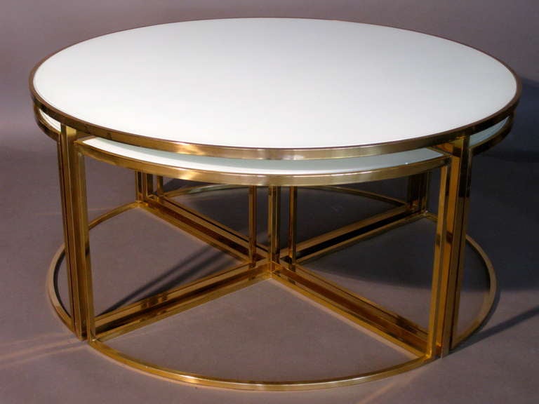 Solid brass round coffee table c.1960s with reverse painted inset glass top with four removable triangular shaped nesting side tables also with reverse painted inset glass tops. Nesting tables can be either totally nested underneath the coffee table