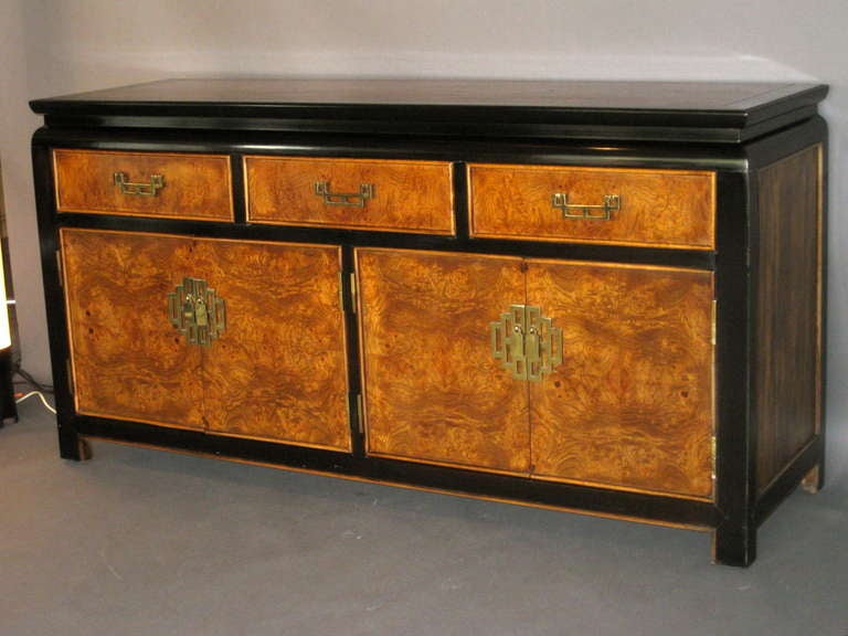 Asian Modern/Chinoiserie burl wood and black lacquer sideboard with brass hardware designed by Raymond Sobata for the Century Furniture Company circa 1950's. Three drawers with two pairs of cabinet doors beneath revealing two storages areas each