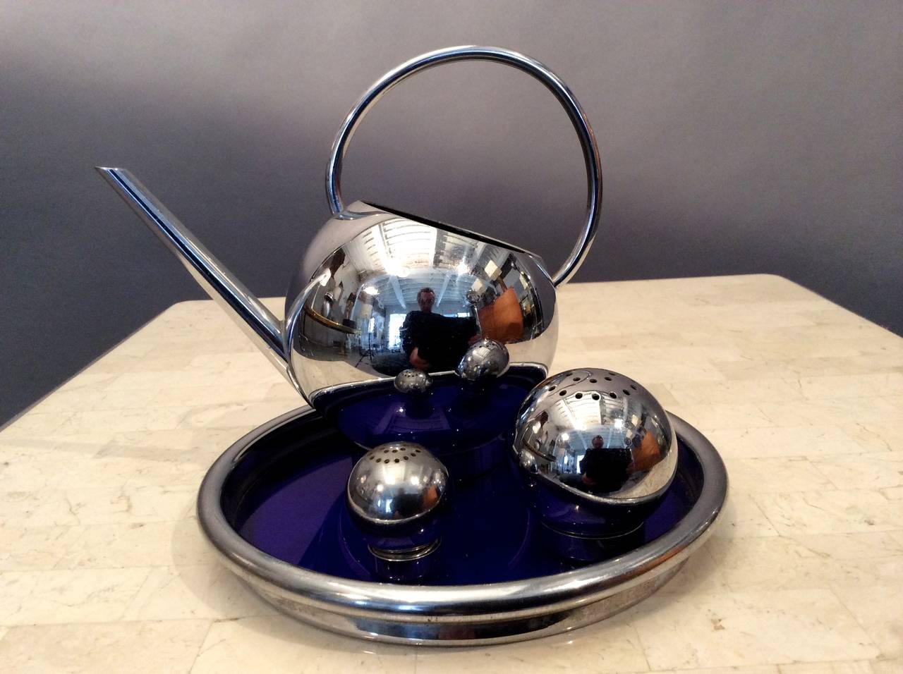 One of Russel Wright's earliest commissions in the mid-1930s was from the Chase Brass & Copper Company for this corn set also now used as a pancake set consisting of pitcher, tray with blue glass insert, and salt and pepper shakers made of