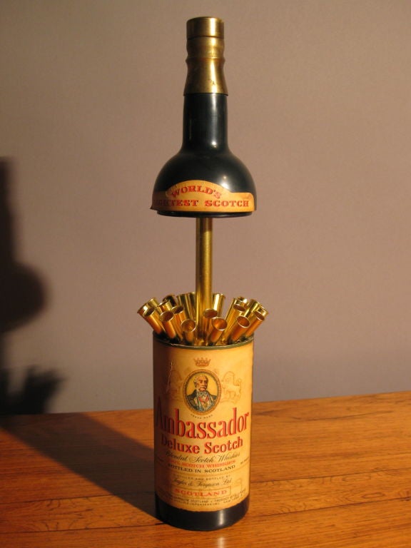 Whimsical cigarette dispenser which looks like a bottle of Ambassador Deluxe Scotch when unopened but when opened dispenses cigarettes and at the same time plays the song 