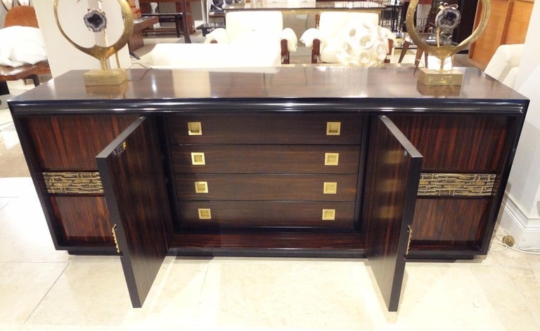 A low four doored console or credenza featuring a body in Palisander with an ebonised front frame and a cast bronze inset panel that runs through the center of all of the doors. The interior of the piece features four drawers also in Palisander in