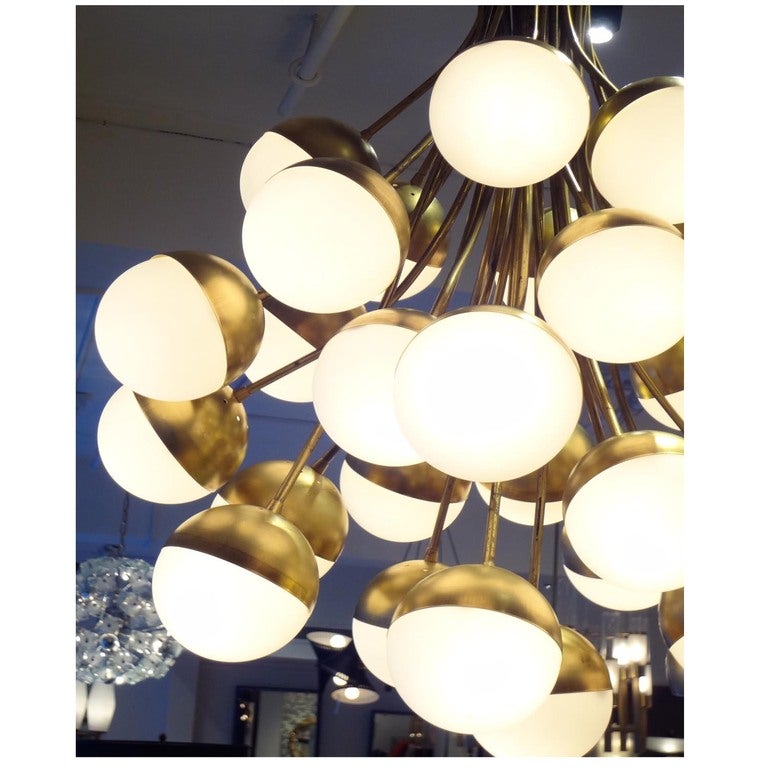 A rare, grand scaled mid century chandelier featuring an inverted bouquet shape in brass with white, opaque glass ball shaped light diffusing shades. There are thirty arms, each with a light source that hang from a large ceiling mounted cup at