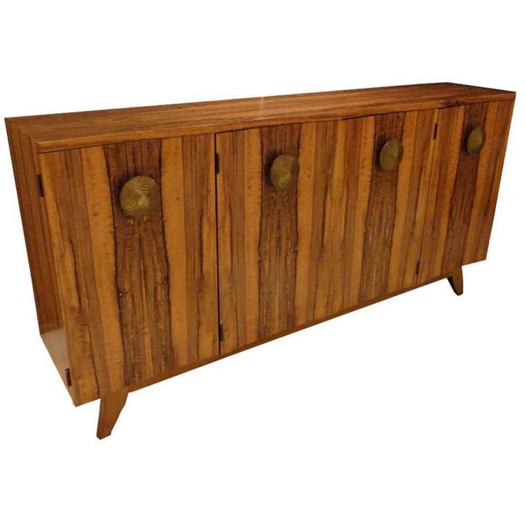 A four doored mid century credenza or sideboard by Gilbert Rohde featuring a body in Rosewood with four doors, each having a concave shaped front and very large round door pulls as well as splayed, tapering legs. This piece is rarely seen in