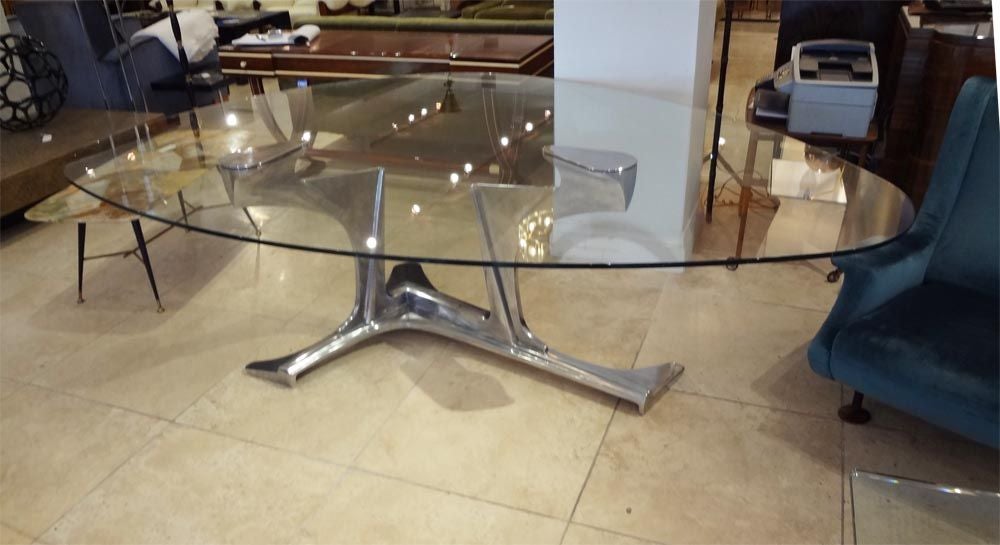 A rare and exceptional dining table featuring an abstract sculptural base in cast aluminum which bisects and supports a organically shaped thick glass top. The table is signed and numbered, 2 of 8, on the base by the artist.  Gerard Mannoni, France