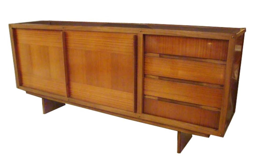 Andre Sornay Mid-Century sideboard featuring a body in cross banded African Mahogany on a Mahogany base with two sliding doors which open to Revel a interior with shelving in original acid green paint, four side drawers with integrated pulls, the
