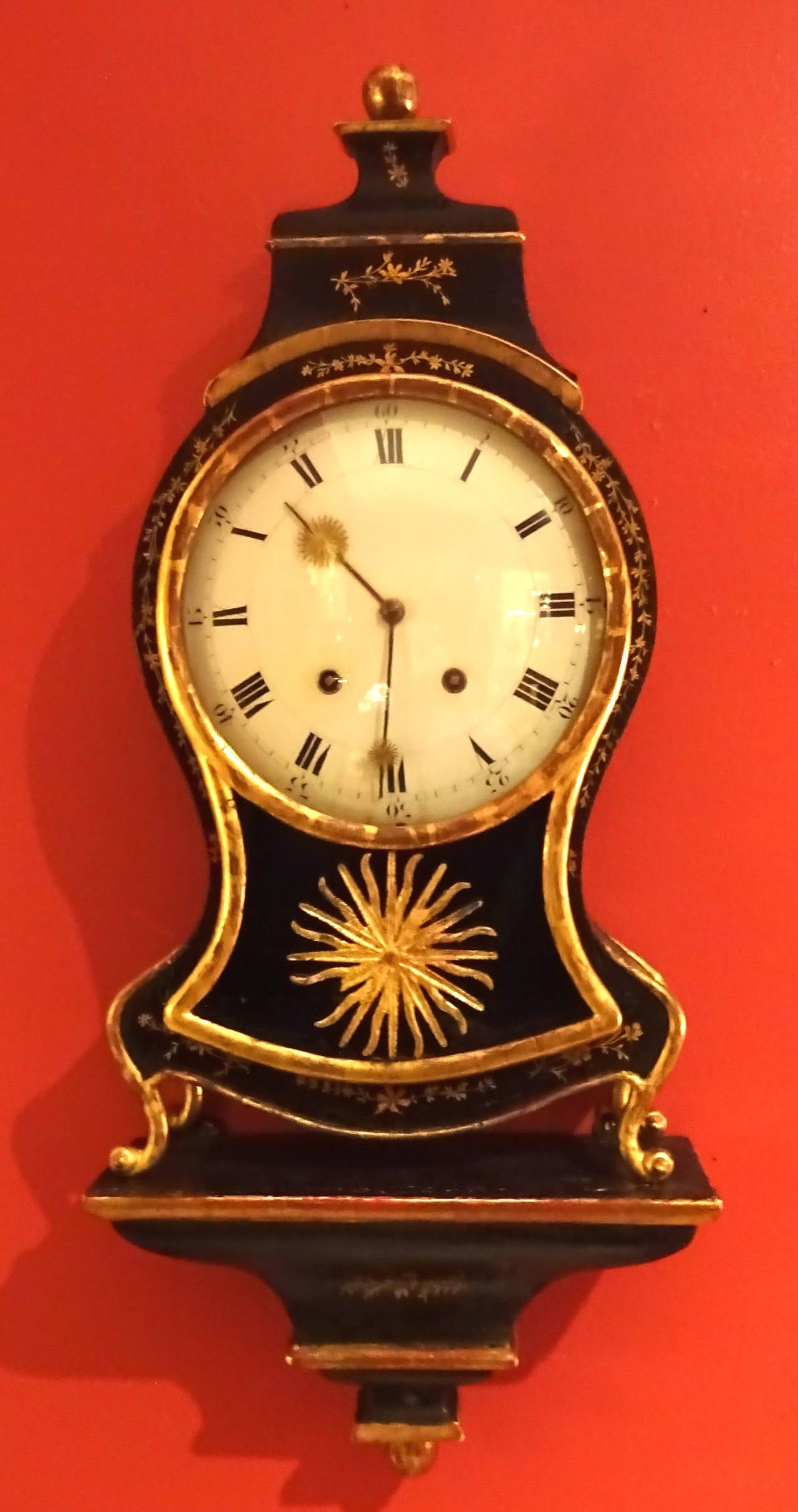 Louis XV style decorative bracket clock in ebony and gilt. The sunburst design on the hands is repeated in a central gilt sunburst located below the face (possibly a later addition). One of the rays of the starburst is missing and could possibly be