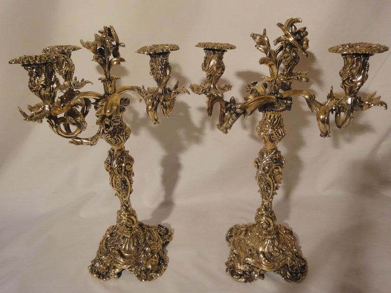 Pair of English Bronze Candelabra Plated to Create the Illusion of Vermeil. The 3 scrolling arms decorated with flowers, leaves & bugs support beautifully detailed candle nozzles with elaborately chased drip pans. The circular bobeches carved with