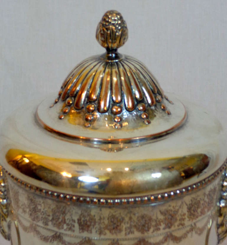 Silver Urn with a lid capped with a finial and two lion's heads with ring handles in their mouths.