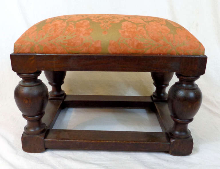 Early 20th century English Tudor style footstool made from oak with modern upholstery.
