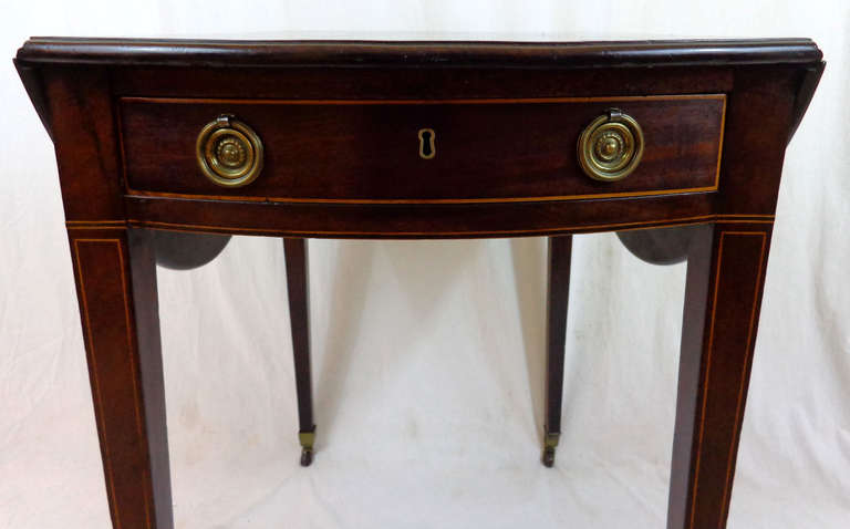 Mahogany Pembroke Table with drop leaves, a single drawer with brass pulls, and tapered legs on brass casters.  Top expands to 37¼
