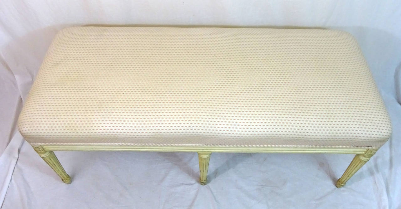 20th century French Louis XVI Style rectangular bench in a painted distressed white finish, and upholstered in a pale cream and citrus colored fabric, formerly employed in a residential project by designer and architect John Astin Perkins.