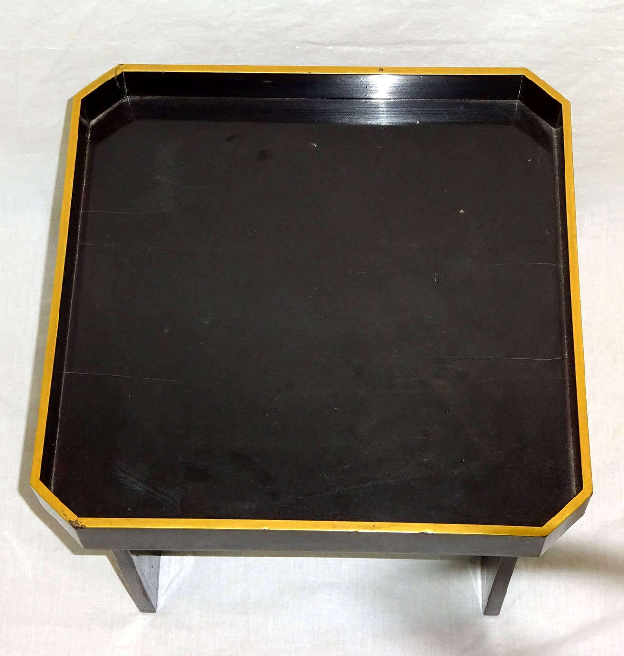 Early 20th century oriental ebonized lacquer small tray table with painted gilt edge resting upon attached square legs.