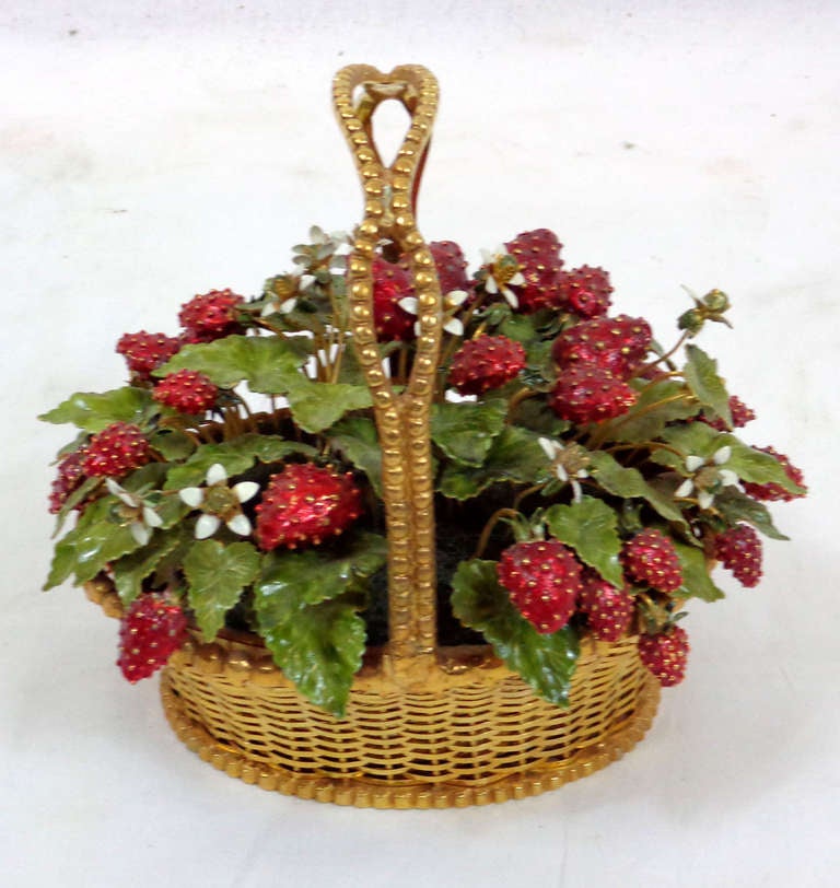 A gilt metal basket filled with faux painted strawberries and green leaves of metal.  The small white flowers are of the same material with glass bead centers.  By Gorham Silver Company, Rhode Island.
