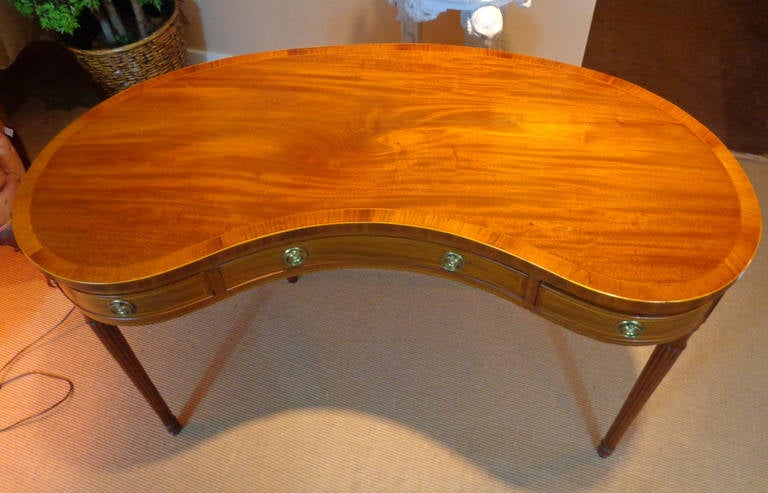 Sheraton style kidney-shaped desk of faded mahogany with banding and stringing.
