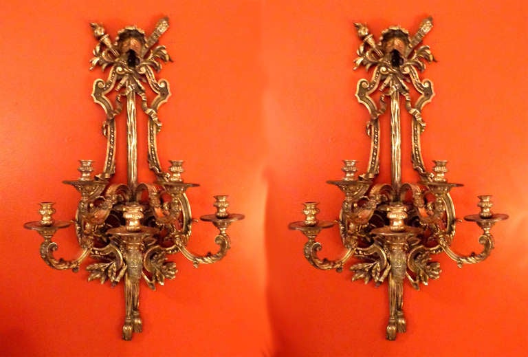 Pair of large Louis XVI Style sconce with 5 candle-bearing arms embellished with ribbons, leaves, tassels, helmets, torches, and a quiver of arrows.  The design is taken from one of the great French Palaces.  Tarnished silver on bronze.