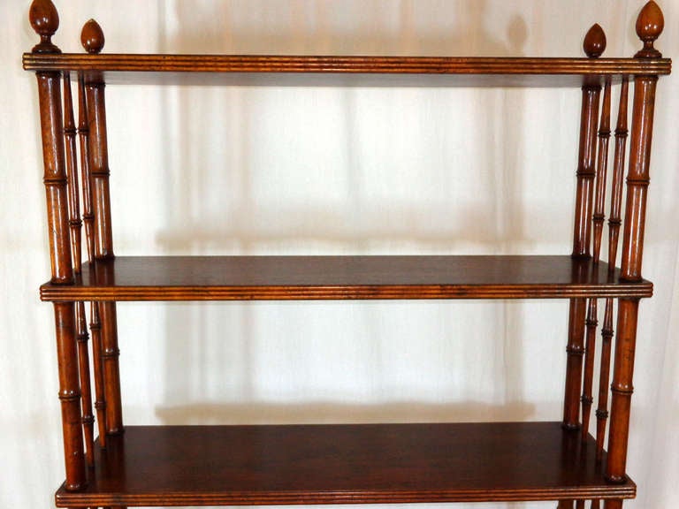 Mid-century Modern bookshelf with faux bamboo supports, finials on the top, standing on four small feet.