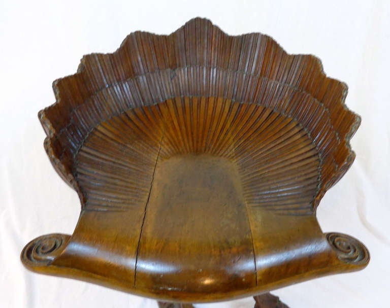 Carved wood grotto chair with swivel seat in a shell-like design.