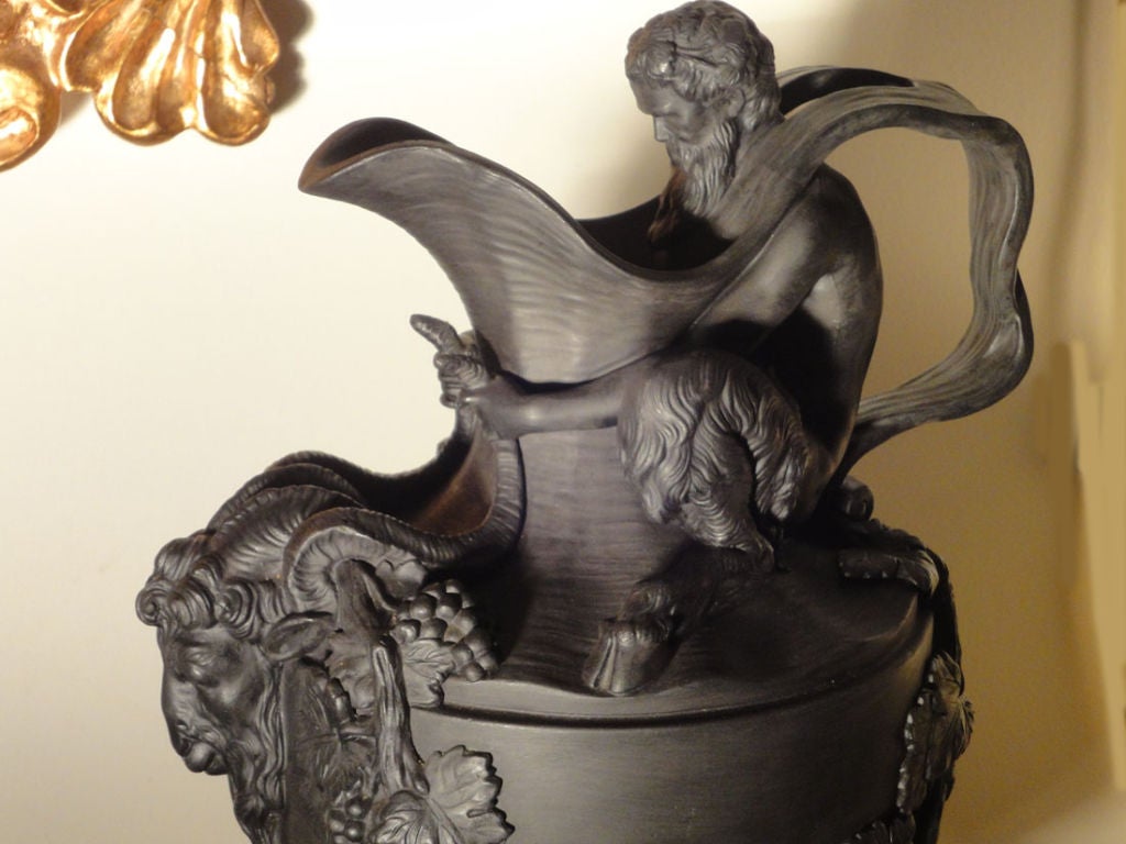 Pair of Wedgwood Black Basalt Urns representing wine & water, & the design is based on early models created by Wedgwood.   The hands & hooves of the Greek god Pan clasping the spout of one urn, & the Greek god Triton's hands & fish tail clasping the